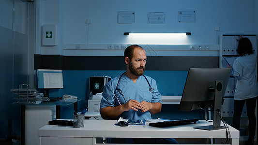 站在医院办公室办公桌前的医疗助理在医疗报告中夜班工作图片
