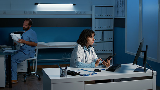 使用平板分析人体射线照相机分析的女专家 在计算机上打字医学专门知识图片