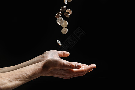 硬币落入一个穷人的手中 在暗底背景微博上提供财政援助 复制空间图片