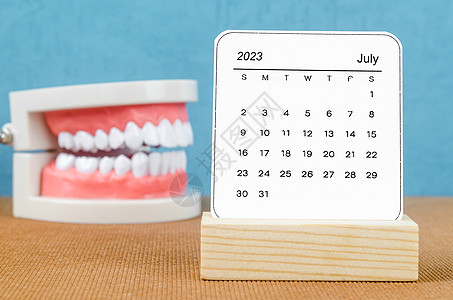 2023年7月的每月日历为2023年 木制桌上有假牙图片