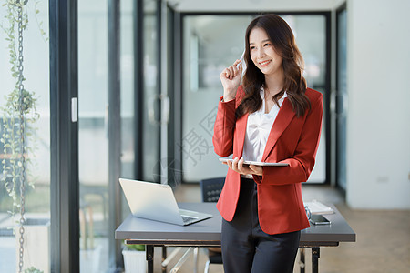 亚洲商业业主或亚洲女性销售商在办公室工作时使用平板电脑摄影商务审计成人职业手机技术药片文书人士图片