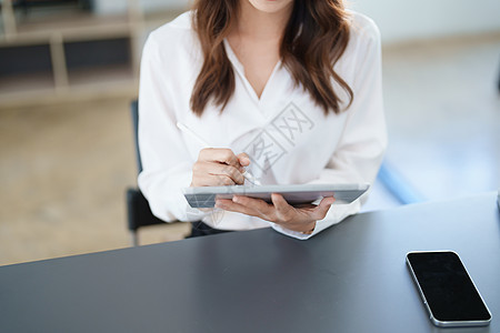 亚洲商业业主或亚洲女性销售商在办公室工作时使用平板电脑女士职业金融文书手机技术成人自由职业者药片摄影图片