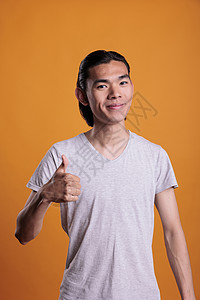 年轻快乐笑笑的亚洲男人 放弃拇指图片