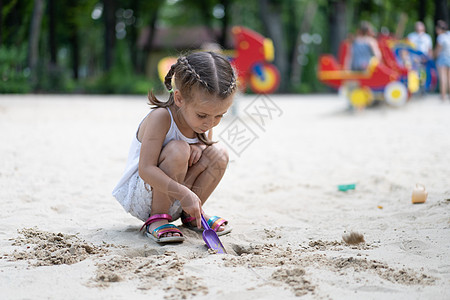 玩沙箱游戏的小女孩 在挖掘沙沙沙幕建筑沙沙图夏季日幸福塑料玩具操场沙坑闲暇小姑娘建筑喜悦幼儿园图片