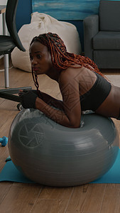 坐在瑜伽螺旋球上做腹部肌肉的健体运动的妇女闲暇房间福利卫生腹肌健身姿势训练练习有氧运动图片