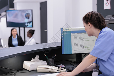 助理在电脑上查看病人检查预约 同时检查文件上的医学专业知识图片