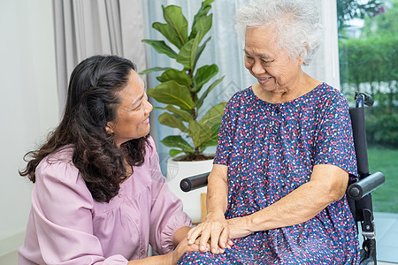 护理员帮助和照料亚洲老年人或老年老年妇女 她们坐在家里轮椅上工作 (请访问InfoFinland上的图片