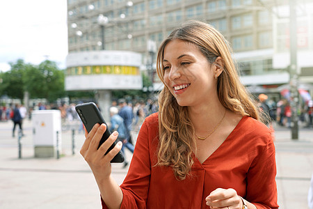 在德国柏林亚历山大广场广场观看智能电话屏幕的快乐临时妇女近距离收看者名单图片