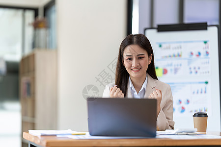 成功的亚洲女青年商业成功实现目标的年轻女商务人士兴奋地举起手来 在办公室用笔记本电脑欢欣鼓舞人士快乐喜悦员工优胜者教育幸福女士微图片