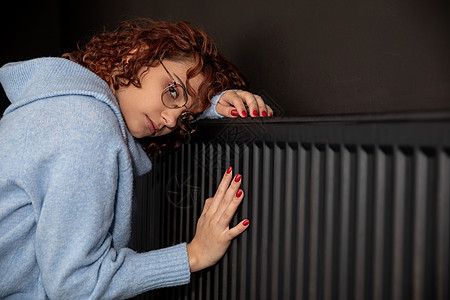 女孩将手缩到暖暖散热器上 温暖了双手生态供暖散热器辐射安装家庭加热控制暖手暖气图片