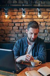 午餐时在市咖啡馆喝咖啡的年轻男子及笔记本电脑工作咖啡店思维白领桌子晚餐大学手机男人食堂餐厅图片