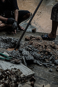 水电工人使用工具 在下雨时修补商业建筑供水的破损水管主干线图片