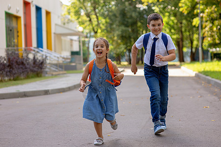 快乐的学童 一个女孩和一个穿着白衬衫 背着背包的男孩逃学图片