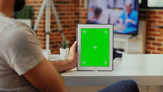 男性自由职业者分析家庭现代平板电脑上的绿屏图片
