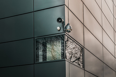 安装在现代建筑墙外的监视摄像头上灯光系统检查玻璃窗树木住宅电视玻璃镜片保安图片