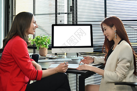 微笑的白人女执行经理与亚洲女同事交谈 讨论现代办公室的商业计划图片