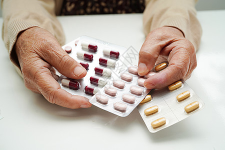 亚洲老年妇女手持避孕药 强有力的健康医疗概念 艾滋病毒艾滋病诊所药店帮助剂量治疗医生制药女性处方药物图片