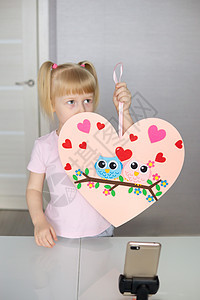 一位博客女孩以心灵的形状为情人节做了一种自觉的手工艺 儿童创造力和手工创作的概念 但是卡片庆典爱好礼物孩子婚礼夫妻孩子们工艺问候图片
