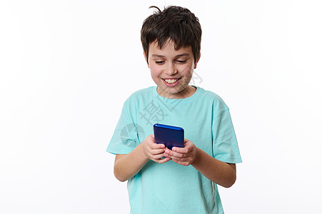 一个快乐快乐的少年男孩在智能手机上玩虚拟网络游戏的白色背景 孤立的肖像图片