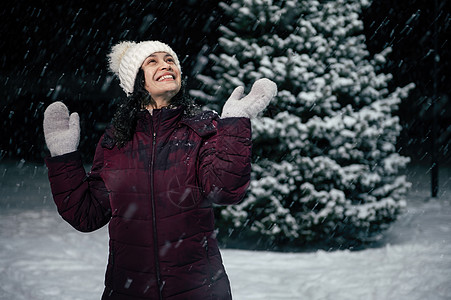 快乐的快乐女人玩得开心 抓雪花 在雪冷的冬夜站在白雪覆盖的大自然上图片