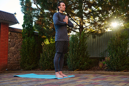 一名活跃的男子在日落时全身沉思 赤脚站在健身垫上 呼吸新鲜空气图片