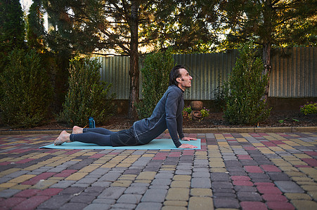 侧视一名运动员 一名运动员在户外练习体重训练时在健身垫上伸展身体图片