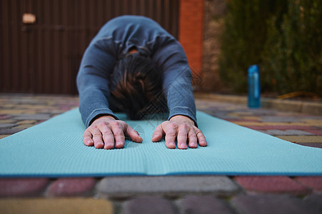 在瑜伽练习期间 有选择地关注男性运动员或瑜伽手在健身垫上和伸展身体时的助行长图片