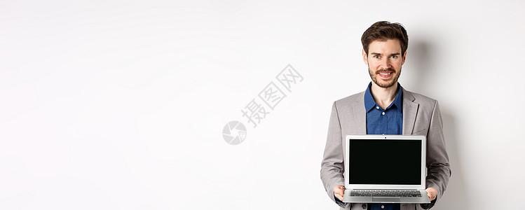 穿着空笔记本电脑屏幕的英俊caucasians商务人士 展示宣传 站在白色背景上工作广告快乐工作室促销技术成人人士生活套装图片