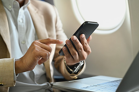 利用机上无线连接处理手提笔记本电脑和手机打字文本的商务客乘员图片