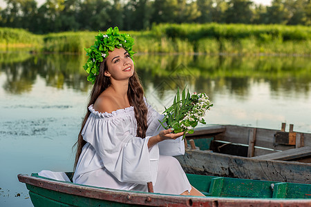 深色头发长发的女神 穿着白色古董礼服 坐在河中央的一条船上花朵魔法若虫神话魅力童话美人鱼成人裙子女孩图片