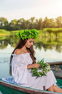深色头发长发的女神 穿着白色古董礼服 坐在河中央的一条船上海滩神话美人鱼童话若虫女孩魅力魔法花朵冒充图片
