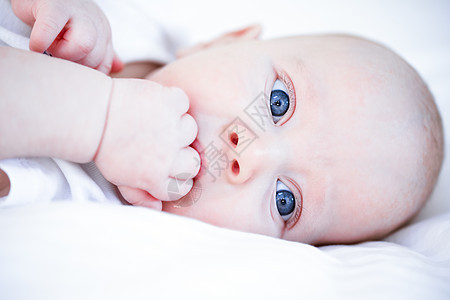蓝眼小婴儿闭着嘴 拳头紧贴近视线的蓝色眼睛肖像图片