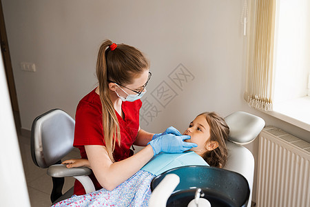 在牙科咨询儿科牙医 儿科牙医检查女童的牙齿以治疗牙痛 儿童牙齿疼痛卫生病人女士医生工作药品专家工具椅子孩子图片