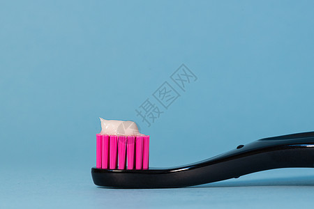 在蓝色背景上用牙膏特写牙刷霓虹粉红色 牙医日概念 牙刷日 复制空间图片
