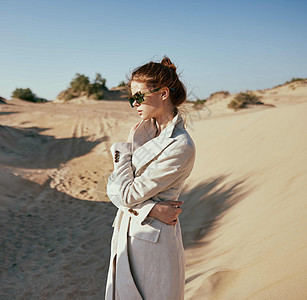 穿着轻夹克和太阳镜的时装女人 在沙漠背景下摆布着快乐幸福红发天空乐趣格子旅行沉思活力微风图片