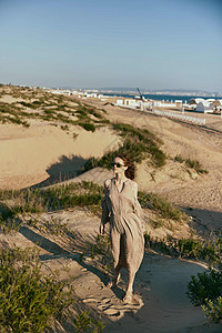 一名休假的女子穿着长裙和墨镜走在赛道上平衡幸福假期沉思日落享受天空活力海滩红发图片