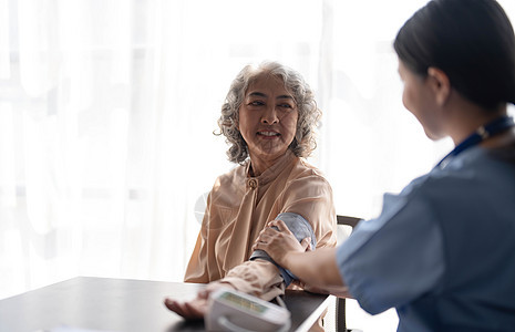 女护士正在为一名老年女性患者测量血压 医生在养老院为一位老年妇女测量血压 女性看护者和老年女性一起在家压力退休女士诊所医疗成人检图片
