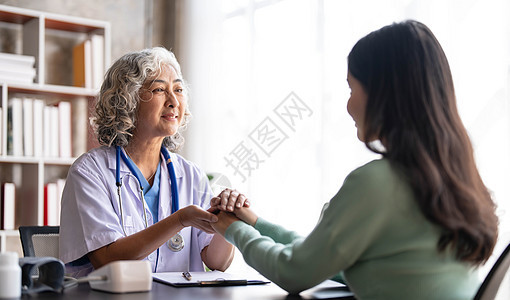 女高级医生正在阅读女病人的病史 并在诊所咨询期间与她交谈 身穿实验室大衣的医生坐在医院办公室的笔记本电脑后面老年药品微笑工作女性图片