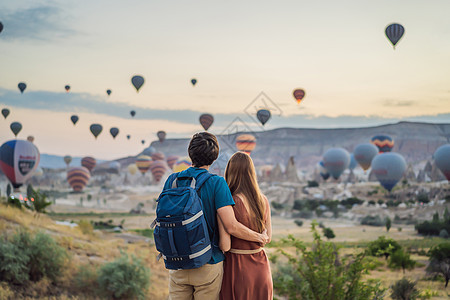 在土耳其卡帕多奇亚 游客们正在看热气球 土耳其概念中的快乐旅行 一对男女在山顶享受美妙的景色天空假期日出悬崖内夫日落冒险气球空气图片