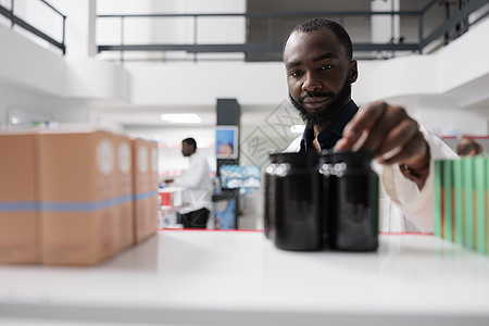 非洲美籍药剂师从药店货架上取药瓶手臂治疗药片架子男人化学家医疗店铺药物瓶子图片
