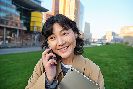 大学生活方式 年轻亚洲学生 有平板和笔记本的女孩在街上走出校园走出去时用移动电话讲课艺术家细胞自由职业者女性界面手机药片街道成人背景图片