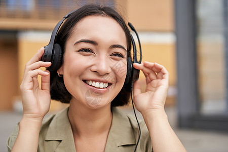 戴耳机的亚洲美女画像 在市中心的街道上听音乐 开心地笑着电话城市快乐青年女士互联网女性青少年商业音乐图片