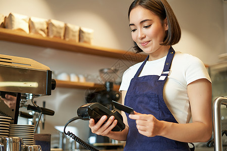 可爱的亚洲女孩 咖啡馆里的咖啡师处理非接触式支付 将信用卡插入 POS 终端 在咖啡店点菜职业柜台咖啡卡片收银机酒吧信用食堂食物图片