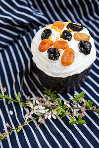 复活节蛋糕用干杏仁和西梅装饰 挂在条纹的蓝色围裙上 开花枝 复活节宗教假日概念图片