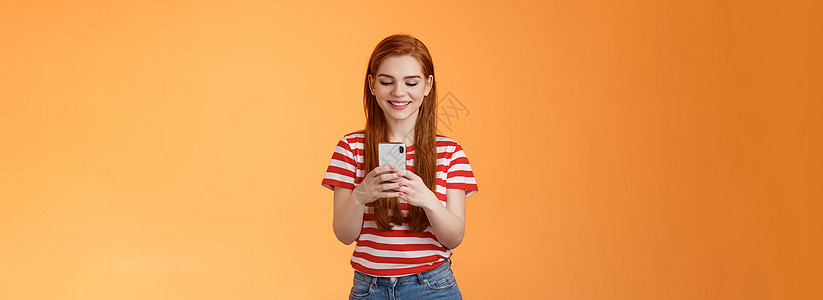 友好外向的现代姜女郎与朋友交流 聊天 发送有趣的模因手持智能手机 微笑快乐的小工具显示 使用社交媒体应用程序享受新设备功能细胞投图片