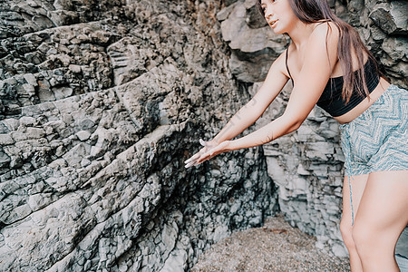 攀登岩石的体育妇女 身材苗条的年轻女子在火山玄武岩洞穴中攀爬 欣赏美丽的海景 女运动员在大自然中训练 女人克服困难的攀登路线肾上图片