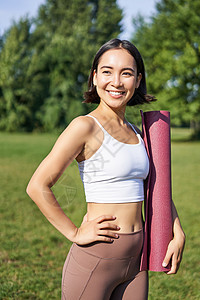 带着橡胶垫微笑的健身女孩 站在公园里穿着制服参加锻炼和体育活动 在草坪上做户外瑜伽快乐日落慢跑者运动装训练福利女士太阳运动成人图片