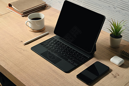 配有无线键盘 智能手机和木制桌上咖啡杯的数码平板电脑图片