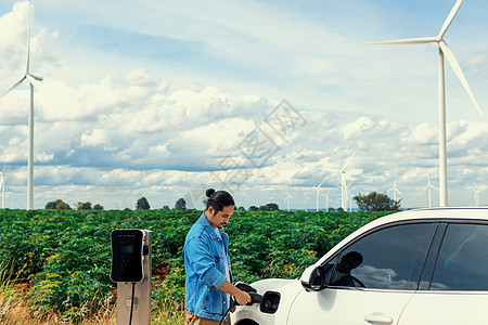 进步的人 他的EV汽车和风力涡轮机 是可再生能源的概念可持续天空运输充值车站绿地插头汽车力量技术图片