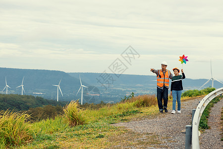 进化工程师和他的儿子 在山上拿着风车玩具呢头盔工人发电机生产场地父母涡轮机商业涡轮工作图片